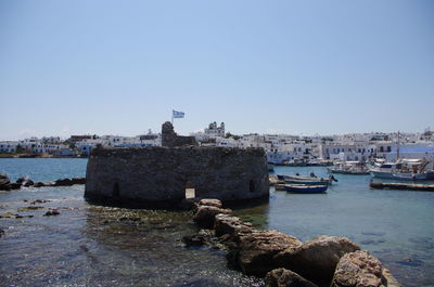 Boats moored at harbor against clear sky