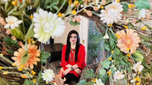 Portrait of woman standing by flowering plants