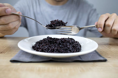 Midsection of person having breakfast on table