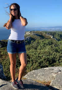 Young woman standing on rock against sky