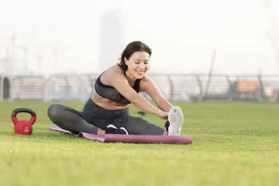 Full length of young woman sitting on grass
