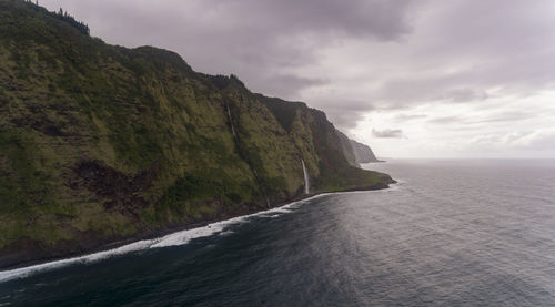 Scenic view of sea by mountains against sky