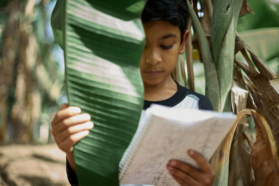 Boy reading book by tree