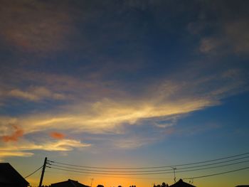 Low angle view of silhouette electricity pylon against sky during sunset