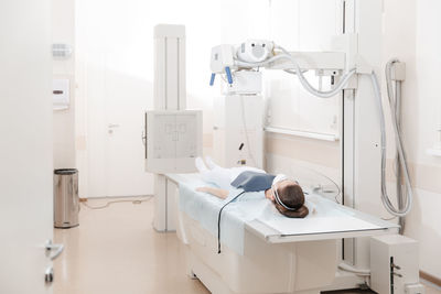 Doctor taking x-ray of patient lying on gurney. hospital radiology room. x-ray machine. 