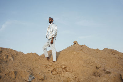 Man wearing silver jacket standing on sand