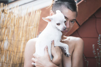 Adorable portrait of strong woman cuddling dog close to face on balcon
