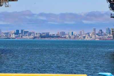 Sea by buildings against sky in city