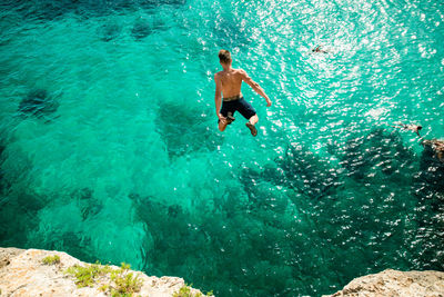 Full length of shirtless man jumping in sea