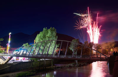 Firework display over river against sky at night