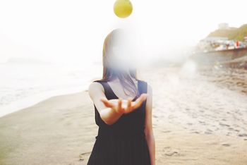WOMAN STANDING ON BEACH AGAINST SEA