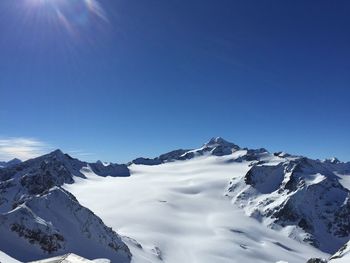 Low angle view of snowcapped mountains against clear blue sky