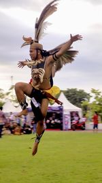 Low angle view of woman jumping against sky