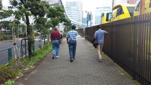 Rear view of three men walking on footpath