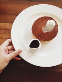 Cropped image of hand holding plate with pancake and coffee cup