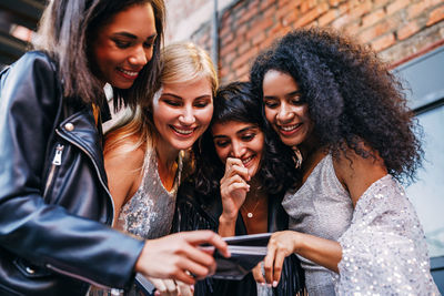 Happy young woman using smart phone in city