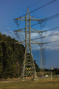 Low angle view of electricity pylon on field against sky