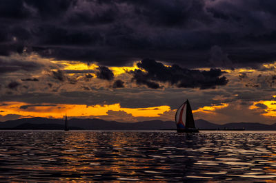 Silhouette sailboat sailing on sea against sky during sunset