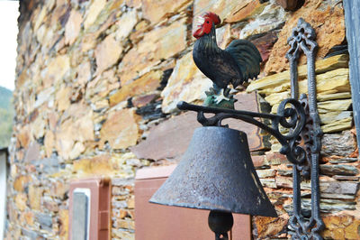 Close-up of antique metallic bell on stone wall