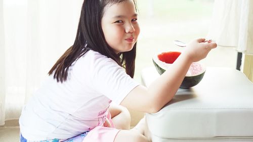 Portrait of smiling girl having watermelon at home