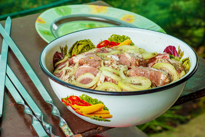 A bowl filled with marinated raw meat for barbecue on fire.