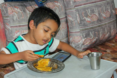 Boy looking away while sitting on table