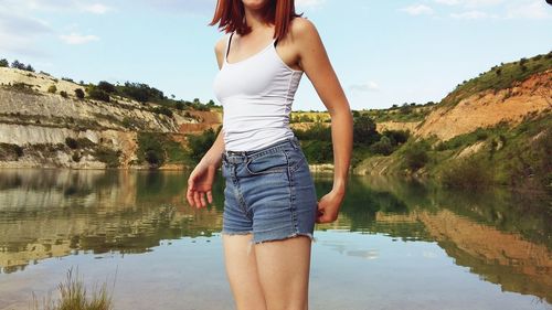Midsection of woman standing against lake
