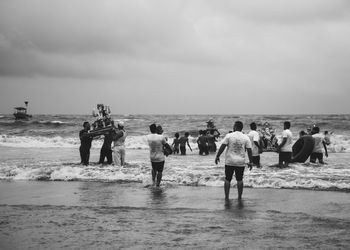 Rear view of people at beach against sky