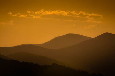 Scenic view of silhouette mountains against orange sky