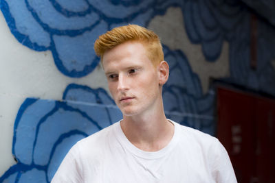 Thoughtful young man standing against wall