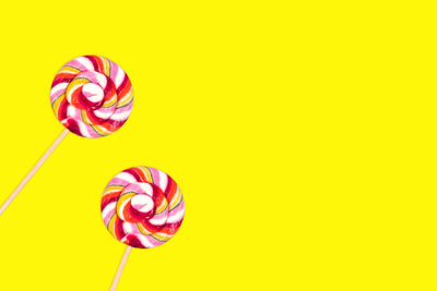 Close-up of multi colored candies against yellow background