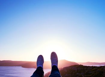 Low section of woman against sky during sunset