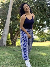 Portrait of young woman standing by tree trunk
