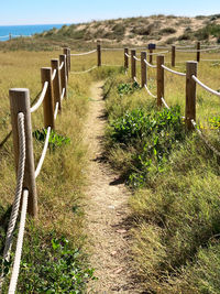 Wooden fence on footpath amidst field