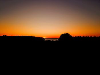 Silhouette landscape against clear sky during sunset