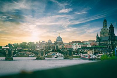 Arch bridge over river amidst buildings against sky in city