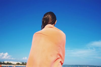 Rear view of woman standing against blue sky