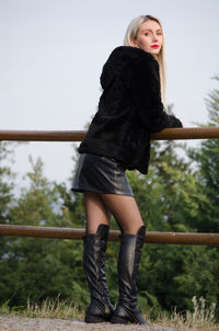 Full length of woman standing on railing against sky