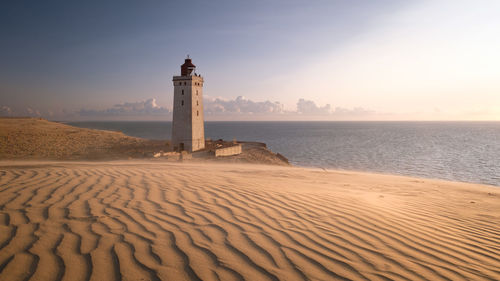 Lighthouse on beach against sky