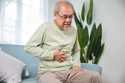 Portrait of senior man sitting on sofa at home