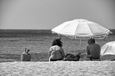 Rear view of women sitting on beach