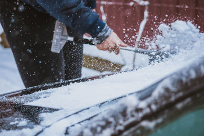 Young teen cleaning snow from the car hood