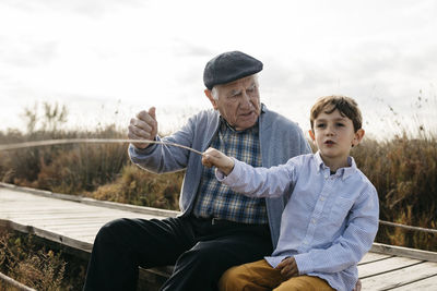 Grandfather and grandson sitting with on boardwalk relaxing