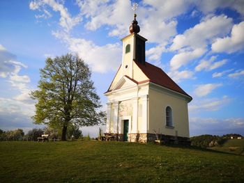 Church on field by building against sky