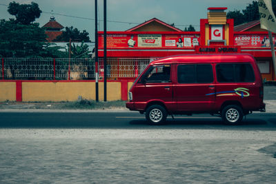 Red car on street against buildings in city