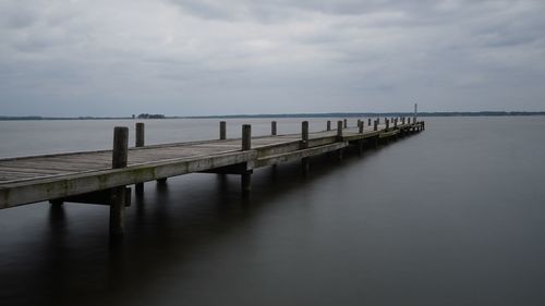 Wooden pier on sea against sky