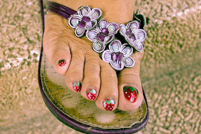 Low section of woman wearing floral flip-flop