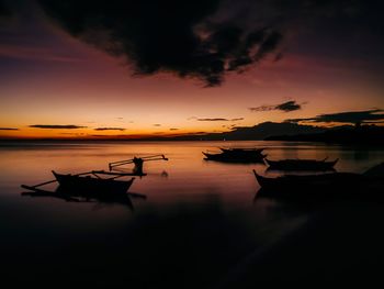 Silhouette boats moored in lake against sky during sunset