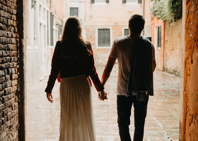 Rear view of friends walking on street in city