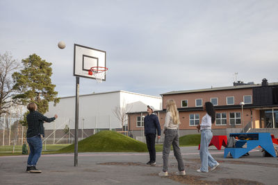 Teenage friends playing basketball outdoors